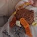 Doudou personnalisé au crochet, marron avec des étiquettes en camaïeu oranges et jaunes.