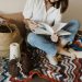 photo issue de pexels, montrant une femme feuilletant un livre de modèles au crochet pour débuter ou continuer un ouvrage. Des bobines de fils sont posées à ses côtés.